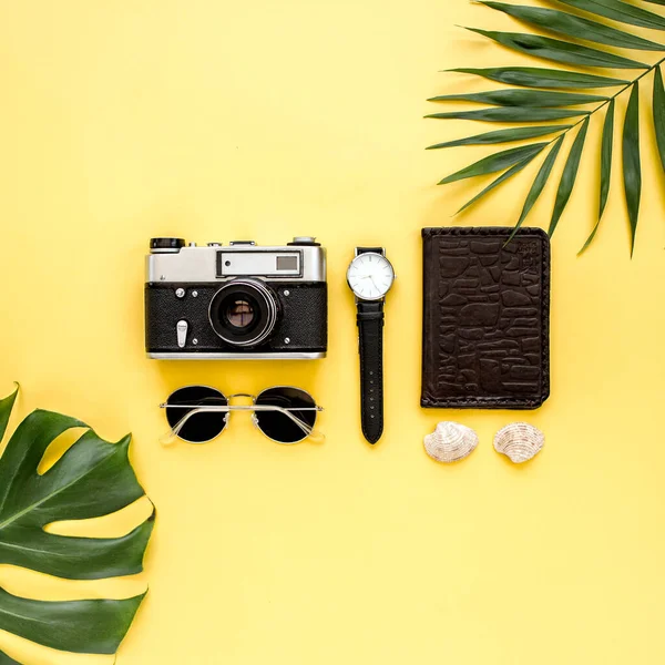 Accessoires de voyage sur fond jaune avec feuille de palme, appareil photo et lunettes de soleil. Couché plat, vue du dessus. — Photo