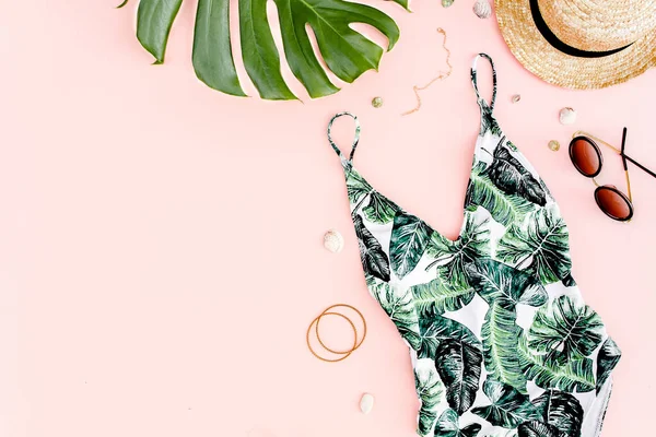Женские пляжные аксессуары: купальник с тропической печатью, соломенная шляпа на розовом фоне. Летний фон. Плоский лежал — стоковое фото