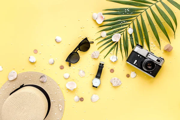 Accesorios para viajeros sobre fondo amarillo con hoja de palma, cámara y gafas de sol. Asiento plano, vista superior. Fondo de verano. — Foto de Stock