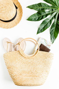 Kadın plaj aksesuarları: rattan çanta, hasır şapka, beyaz arka planda tropikal palmiye yaprakları. Seyahat kavramı. Yaz dönemi. Düz yatıyordu, üst 