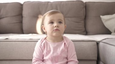 Televizyon izlerken küçük şirin bir çocuk portresi. Genç kız oturma odasında televizyon izler. Konsept video oyunu, eğlence, duygular, aile. Çocuk televizyon izliyor, küçük kızın yüzünü kapatıyor, çocuk gibi bakıyor..