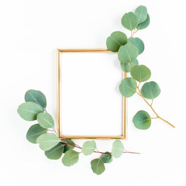 Altın çerçeve yeşil dallar ve beyaz arka planda okaliptüs yapraklarıyla süslenmiştir. Düz uzan, üst görünüm