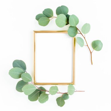 Altın çerçeve yeşil dallar ve beyaz arka planda okaliptüs yapraklarıyla süslenmiştir. Düz uzan, üst görünüm