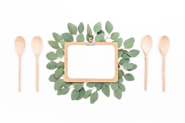 Çerçeve - okaliptüs dallarıyla süslenmiş, beyaz arka planda izole edilmiş bir pano. Düz uzan, üst görünüm