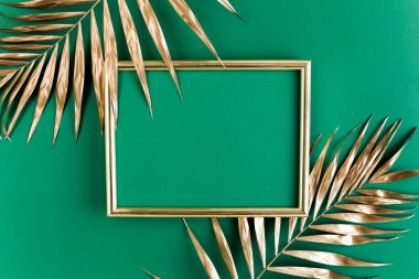 Altın tropikal palmiye yaprakları ve yeşil arka planda fotoğraf çerçevesi. Düz konum, üst görünüm minimum konsept.