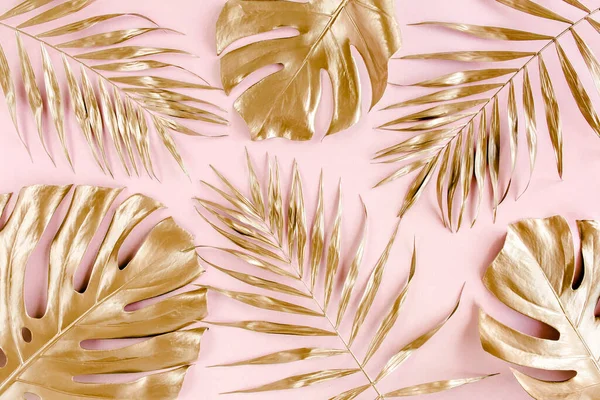 Gold tropical palm leaves Monstera on pink background. Flat lay, top view minimal concept.