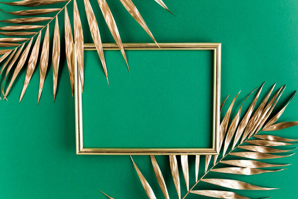 Золотые тропические пальмовые листья и рамка на зеленом фоне. Плоская кладка, вид сверху минимальная концепция.