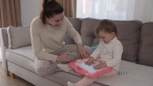 Egy kislány anyával mágneses táblára rajzol. Az oktatási folyamat koncepciója. 4k — Stock videók