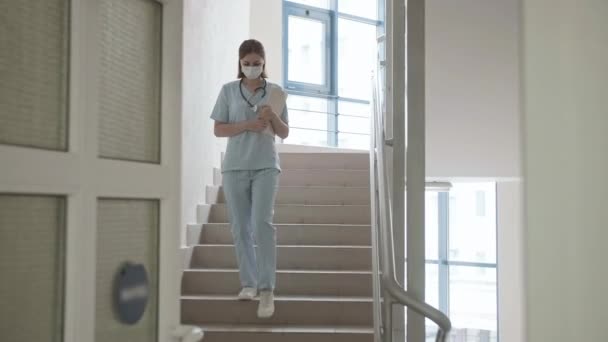 Maskeli doktor hastanenin merdivenlerinde yürüyor. — Stok video