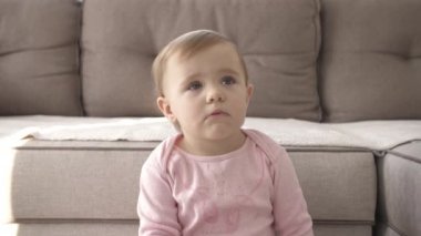 Televizyon izlerken küçük şirin bir çocuk portresi. Genç kız oturma odasında televizyon izler. Konsept video oyunu, eğlence, duygular, aile. Çocuk televizyon izliyor, küçük kızın yüzünü kapatıyor, çocuk gibi bakıyor..