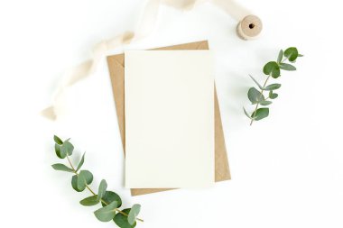 Sahte davetiye, boş tebrik kartı ve yeşil yapraklar okaliptüs. Düz yatış, üst görünüm.