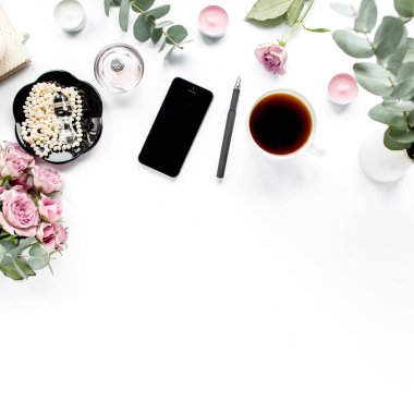 Ofis masası. Çalışma alanı boya fırçası, dizüstü bilgisayar, pembe çiçekler, beyaz arka planda telefon. Düz kompozisyon. Üst görünüm, ev ofis çalışma alanı