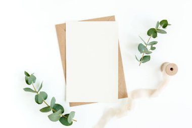 Sahte davetiye, boş tebrik kartı ve yeşil yapraklar okaliptüs. Düz yatış, üst görünüm.