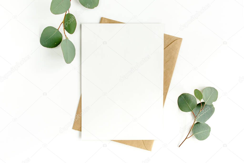 Mockup invitation, blank greeting card and green leaves eucalyptus. Flat lay, top view.