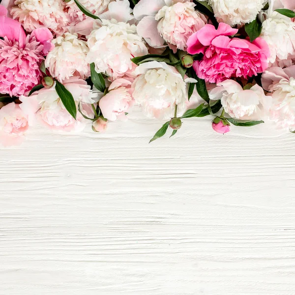 Corona de marco floral hecha de brotes de flores de peonías de color rosa y beige, ramas de eucalipto y hojas aisladas sobre fondo de madera blanca. Piso tendido, vista superior — Foto de Stock
