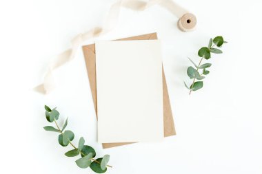 Sahte davetiye, boş tebrik kartı ve yeşil yapraklar okaliptüs. Düz yatış, üst görünüm.