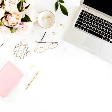 Düz uzanmış kadınların ofis masası. Dizüstü bilgisayarı olan bir kadın çalışma alanı, pembe şakayık buketi, beyaz arka planda aksesuarlar. Üst görünüm kadınsı arkaplan.