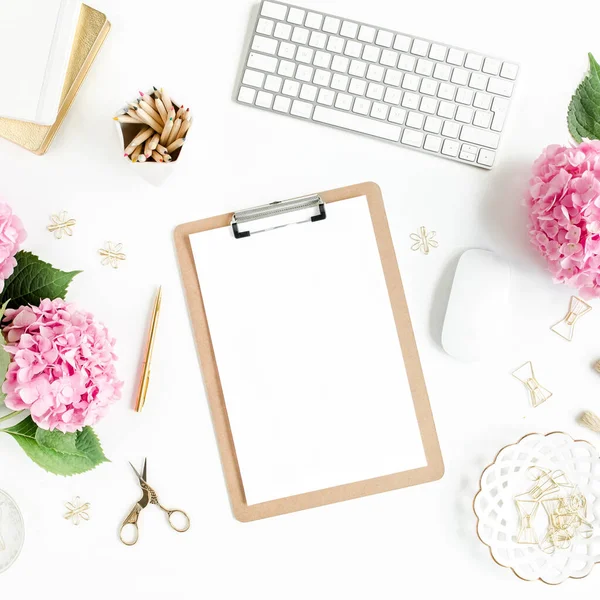 Meja wanita yang bergaya. Ruang kerja dengan papan klip, komputer, bouquet hydrangea, aksesoris pada latar belakang putih. Berbaringlah. Tampilan atas. — Stok Foto