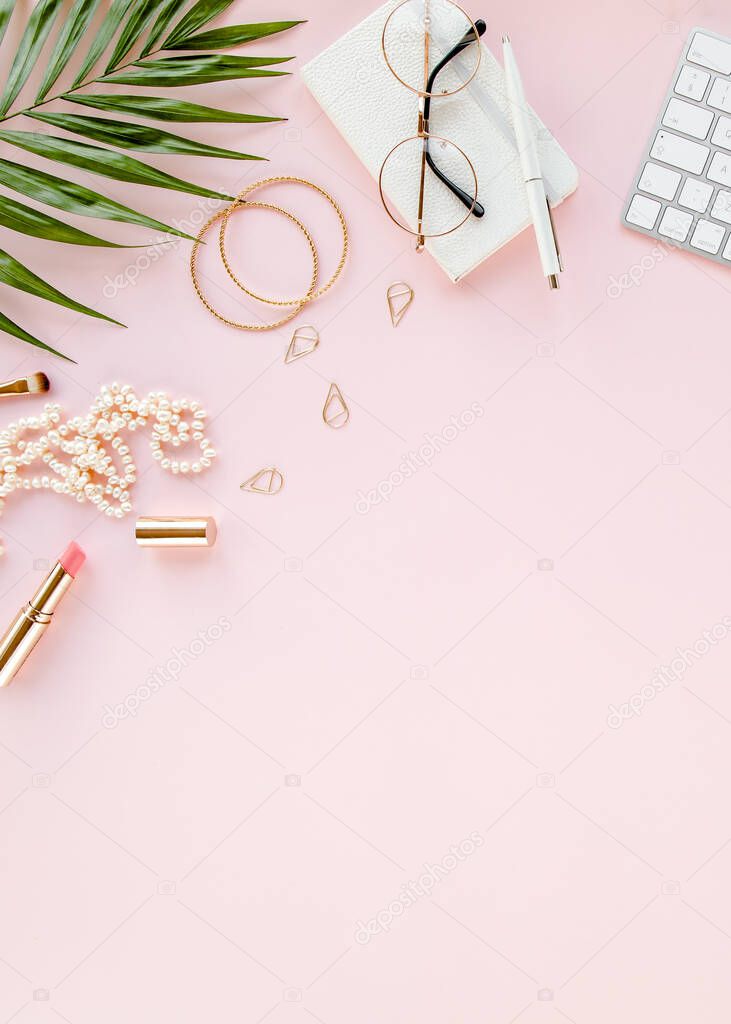 Office table desk with computer, green leaves palm, clipboard. Top view. Flat lay. Home office workspace. Womens accessories on pink background. 