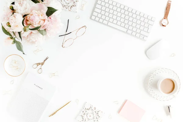 Platte vrouwelijke bureau. Vrouwelijke werkruimte met computer, roze pioenrozen boeket, accessoires op witte achtergrond. Top view vrouwelijke achtergrond. — Stockfoto