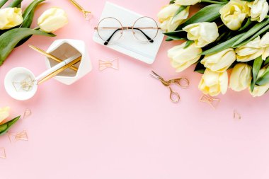 Lale çiçeği buketli, altın aksesuarlı, pembe arka planlı bir kadın çalışma alanı. Düz uzanmış kadınların ofis masası. Üst görünüm kadınsı arkaplan