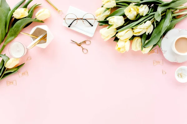 Lale çiçeği buketli, altın aksesuarlı, pembe arka planlı bir kadın çalışma alanı. Düz uzanmış kadınların ofis masası. Üst görünüm kadınsı arkaplan