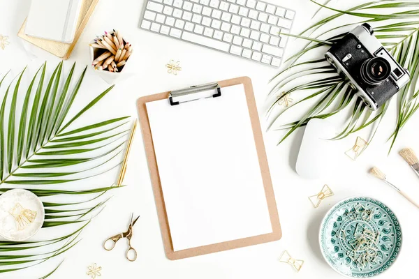 Flat lay mesa de escritório em casa. Espaço de trabalho feminino com computador, área de transferência, folhas de palma tropicais, acessórios sobre fundo branco. Vista superior. — Fotografia de Stock