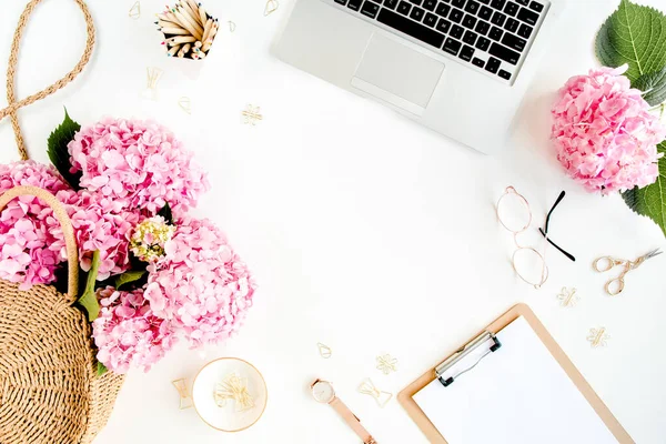 Ruang kerja dengan papan klip, laptop, bouquet hydrangea, aksesoris pada latar belakang putih. Meja wanita yang bergaya. Berbaringlah. Tampilan atas. — Stok Foto