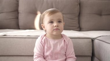 Televizyon izlerken küçük şirin bir çocuk portresi. Genç kız oturma odasında televizyon izler. Konsept video oyunu, eğlence, duygular, aile. Çocuk televizyon izliyor, küçük kızın yüzünü kapatıyor, çocuk gibi bakıyor..