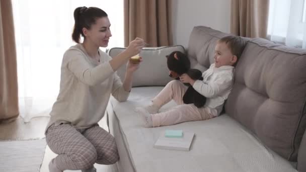 Mujer alimentando a un niño con cuchara. Mamá alimentar al bebé con puré de alimentos. — Vídeos de Stock