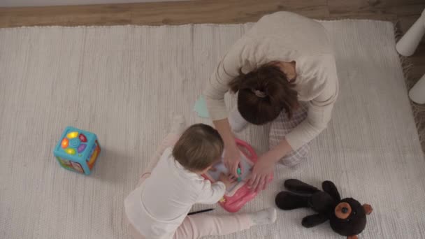 Ευτυχισμένη οικογένεια μητέρα διδασκαλία χαριτωμένο κορίτσι παιδί παίζει σε ζεστό πάτωμα στο σπίτι — Αρχείο Βίντεο