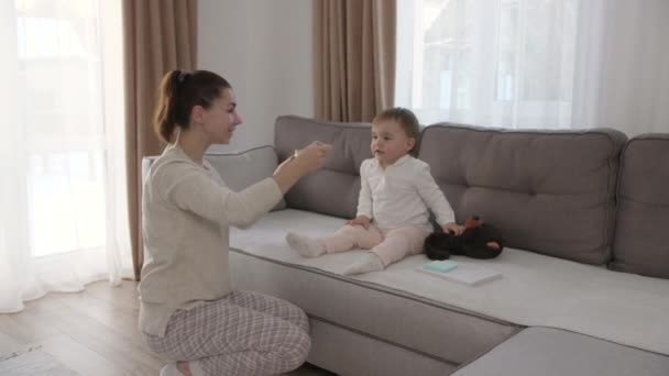 Mujer alimentando a un niño con cuchara. Mamá alimentar al bebé con puré de alimentos. — Vídeos de Stock