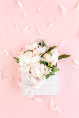 Pembe arka plandaki çiçekler için bir zarfın içinde bej bir buket şakayık. Minimum çiçek konsepti tebrik kartı. Düz yatış, üst görünüm. 