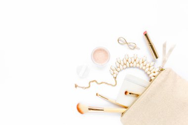 Bej makyaj çantası, makyaj fırçası, kozmetik, beyaz arka planda altın aksesuarlar. Düz kompozisyon. Dergiler, sosyal medya. Üst Manzara. Düz yatıyordu. 