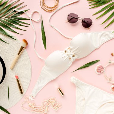 Gezgin aksesuarları, kadınlar yaz bikini takımı, pembe arka planda tropikal palmiye yaprağı dalları. Seyahat tatili konsepti. Düz yatış, üst görünüm. 