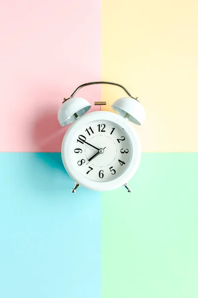 White alarm clock on colorful background. Trendy minimal style. Beauty and fashion concept. Flat lay composition. Top view. — Stock Photo, Image