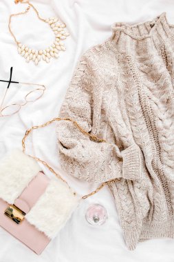 Beyaz arka planda kadın kıyafetleri ve aksesuarları. Kadınların sıcak süveteri, çantası, gözlükleri. Alışveriş konsepti. Düz yatış, üst görünüm. 