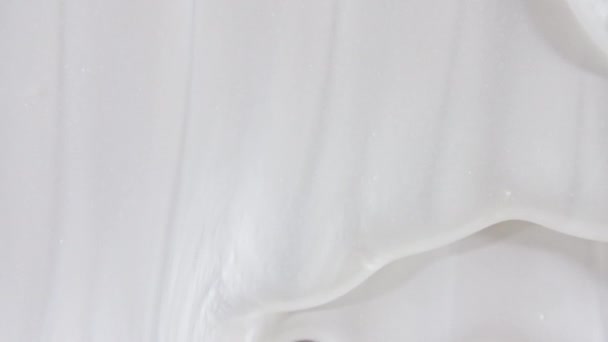 Weißes kosmetisches Gel mit abfließender Flüssigkeit auf einer weißen Oberfläche. Makroschock — Stockvideo