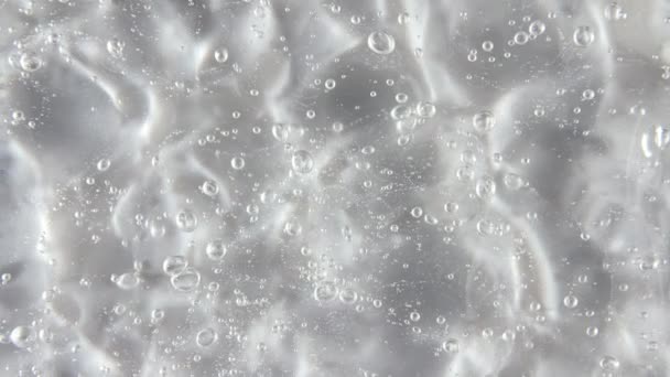 Рухи, обертання рідкого крем-гелю прозорою косметичною текстурою з бульбашками. Органічна косметика, медицина. Вид зверху. Повільний рух — стокове відео