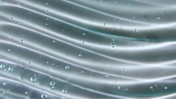 Textura de suero azul, fondo de gel líquido transparente. Movimiento de la muestra transparente de productos para el cuidado de la piel con burbujas. Vista superior. Macro Shot — Vídeos de Stock