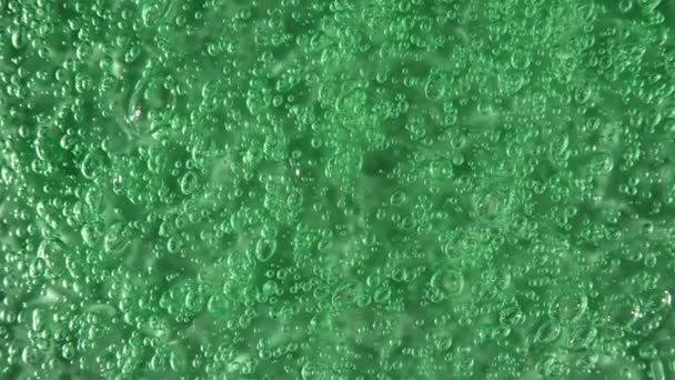 La crema verde líquida, el movimiento cosmético del gel fluido, la rotación sobre la superficie. Muestra de productos de belleza para el cuidado de la piel con burbujas. Vista superior. Movimiento lento. — Vídeos de Stock