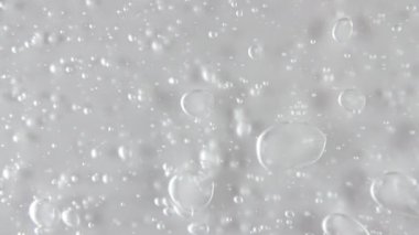 Şeffaf sıvı jel arka plan, açık serum dokusu. Hareket, cilt bakımı, baloncuklu ürün örneği. Üst Manzara. Makro Vuruş