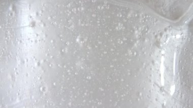 Beyaz sıvı jel arka plan, berrak serum dokusu. Hareket, cilt bakımı, baloncuklu ürün örneği. Üst Manzara. Makro Vuruş