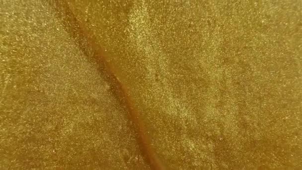 Liquide de gel d'or avec écoulement vers le bas sur la surface. De l'or fondu. Superposition de peinture liquide jaune étincelante. Macro Shot — Video