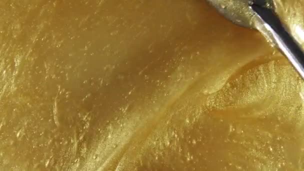 Жидкий металлический золотой фон, текстура. Сверкающий желтый жидкий поток краски накладывается крупным планом. Движение, вращение косметического продукта. Медленное движение — стоковое видео