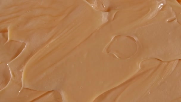 Motion of the Liquid cream, beige cosmetic texture with rotation. Contouring, Make up smears background. Beauty skincare product sample. Slow motion. Top view. 4K UHD video — Stock Video