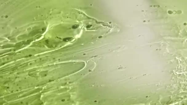 Nata líquida verde, movimento de fluido de gel cosmético, rotação em uma superfície. Amostra de produto de beleza skincare com bolhas. Vista superior. Movimento lento. — Vídeo de Stock