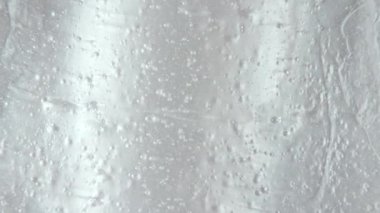 Beyaz sıvı jel arka plan, berrak serum dokusu. Hareket, cilt bakımı, baloncuklu ürün örneği. Üst Manzara. Makro Vuruş