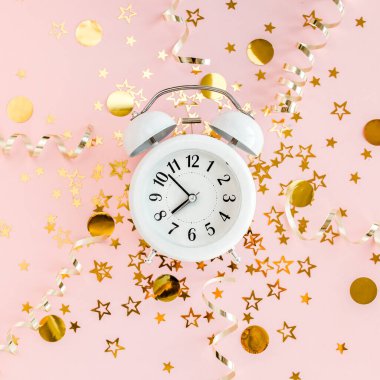 Alarmlı saat, altın yıldızlı konfeti kaplıydı. Pembe, şenlikli bir arka planda süsleme vardı. Noel ya da yeni yıl şablonu. Renkli bir kutlama, doğum günü.