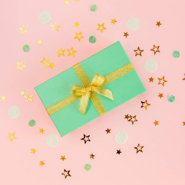 Hediye ya da hediye kutusu ve pembe arka planda yıldız konfetisi. Renkli bir kutlama, doğum günü. Noel ya da yeni yıl şablonu. Düz yatış, üst görünüm 